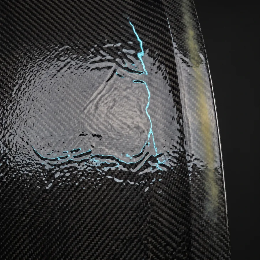 Wet-lay carbon panel showing resin pooling and weave distortion