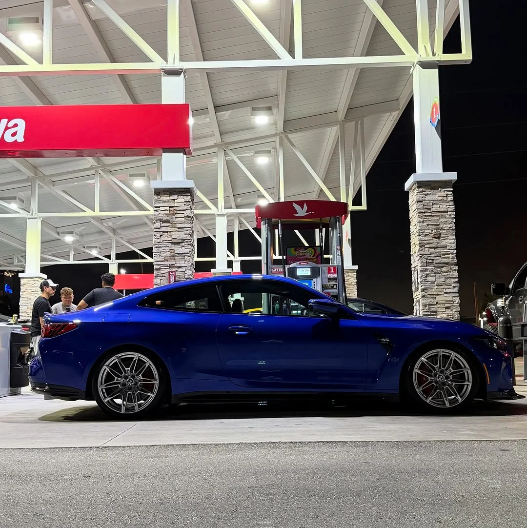 Blue G82 M4 side profile at a fuel station at night